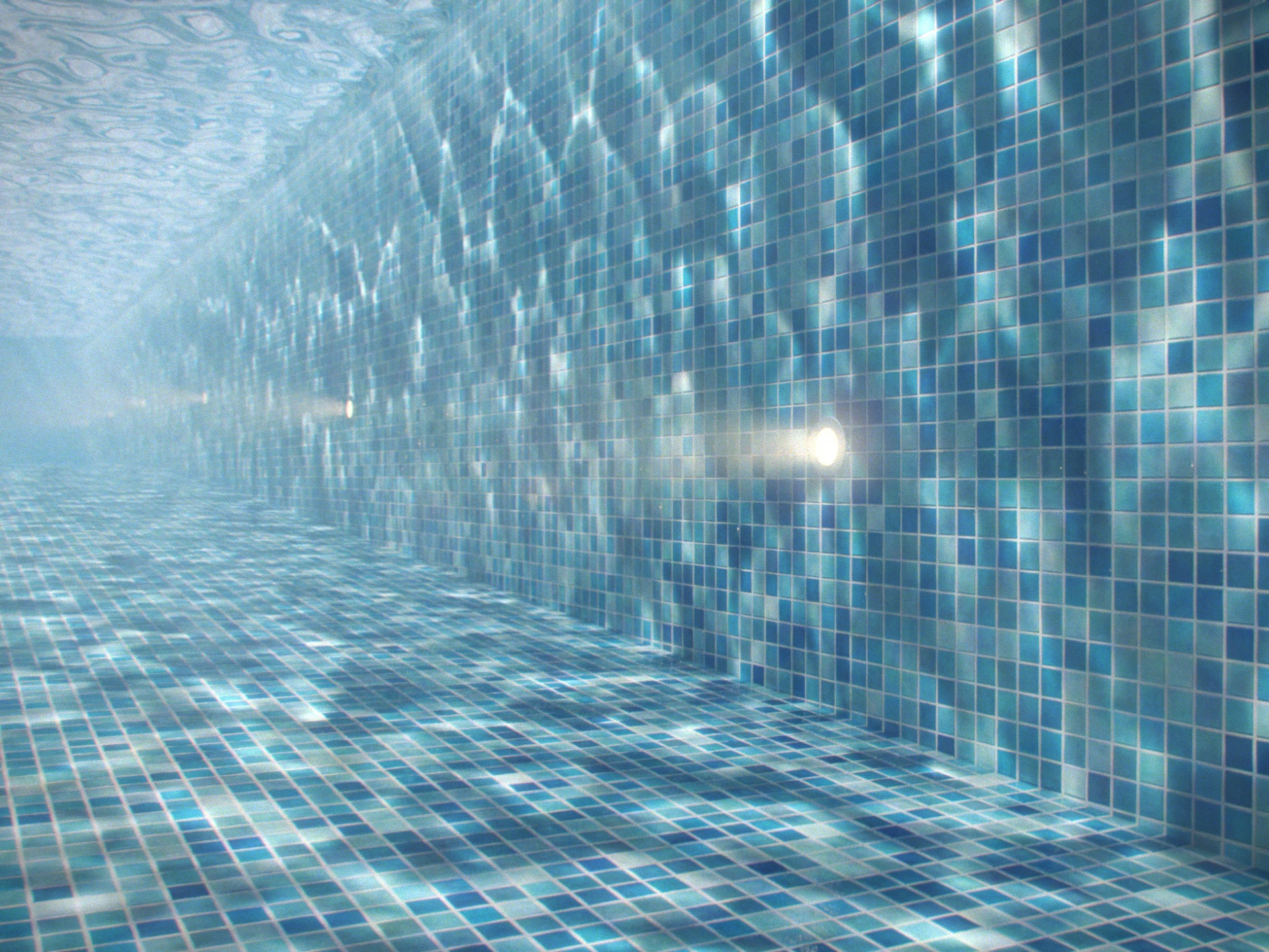 Submersible lighting fixture mounted to a swimming pool